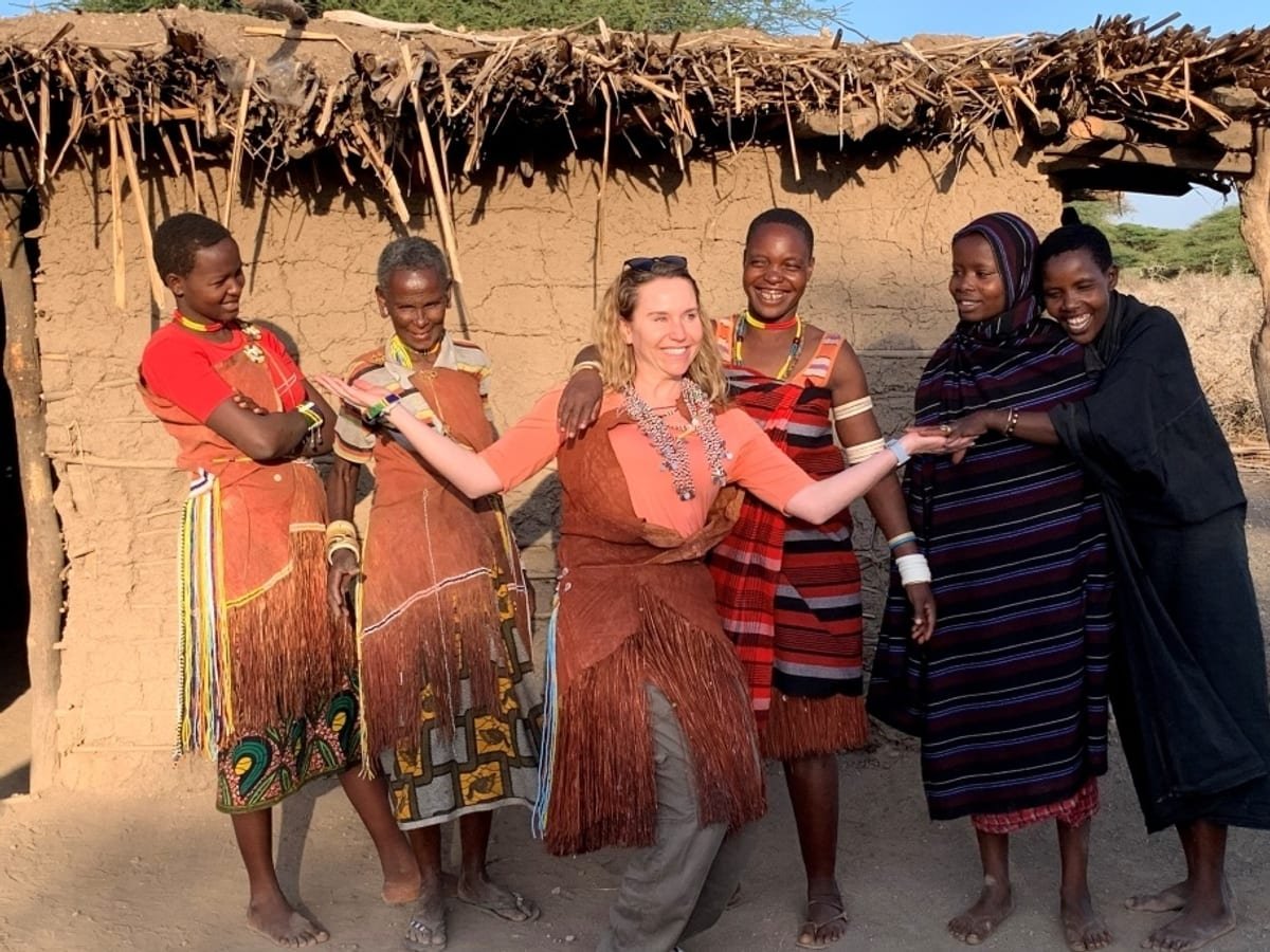 A visitor welcomed by Datoga women outside a homestead