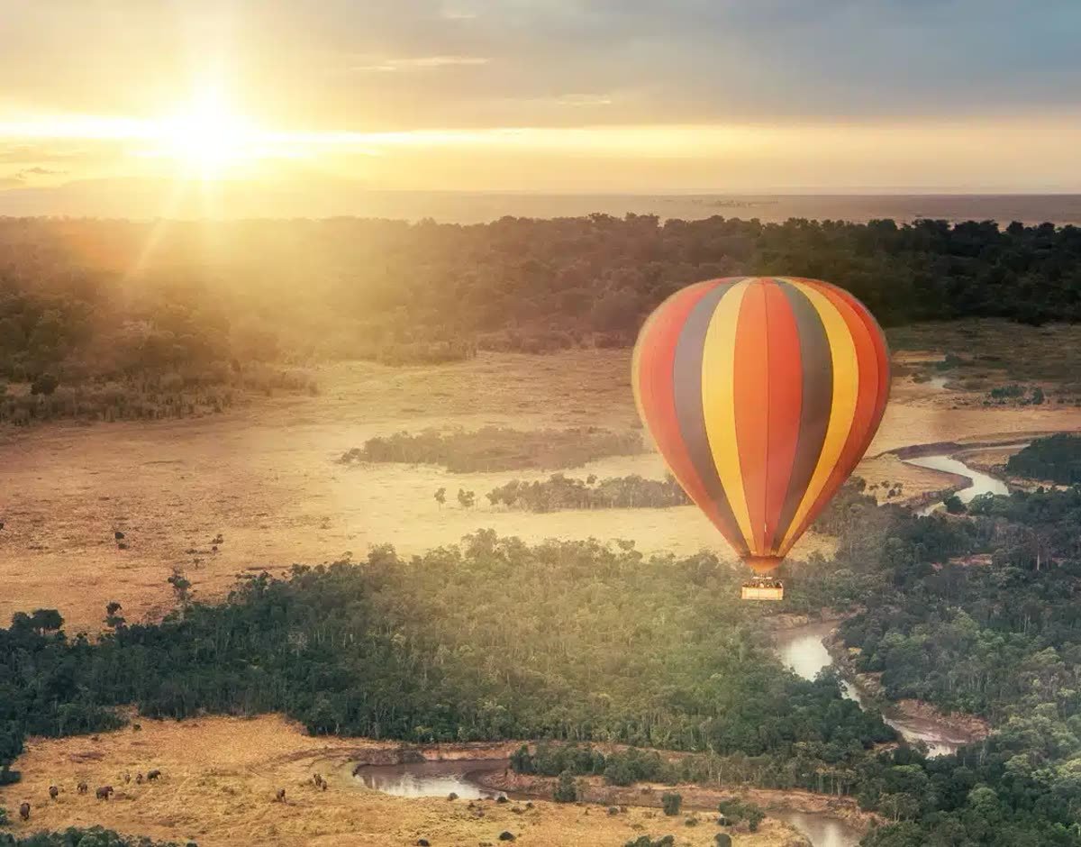 A balloon drifting over the landscape at sunrise