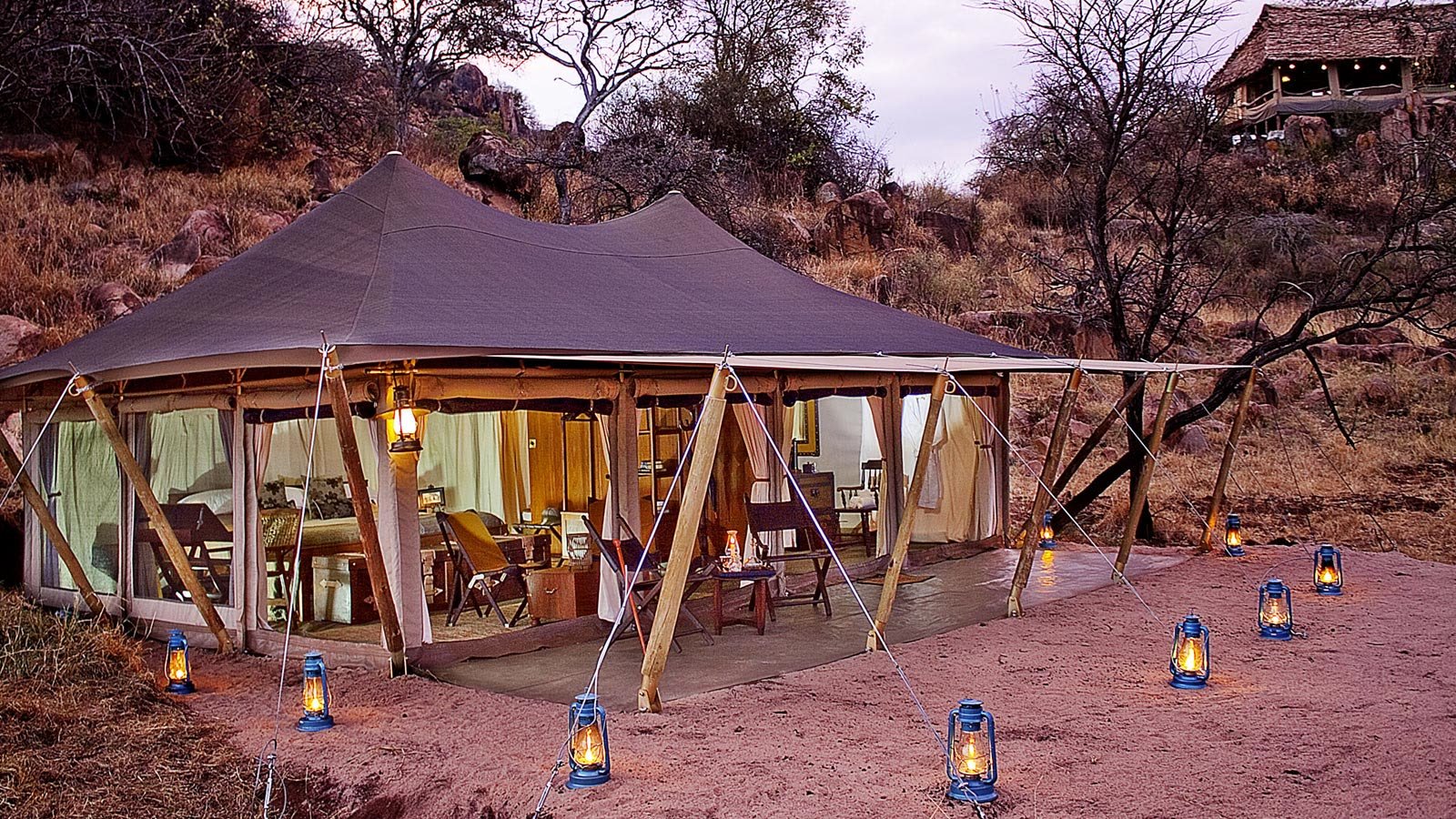 A lantern-lit canvas tent at Serengeti Pioneer Camp at dusk